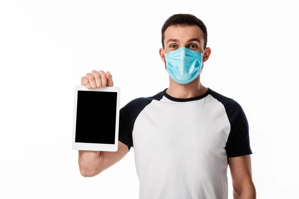 Людина в синій медичній масці тримає цифровий планшет з порожнім екраном ізольовано на білому — стокове фото