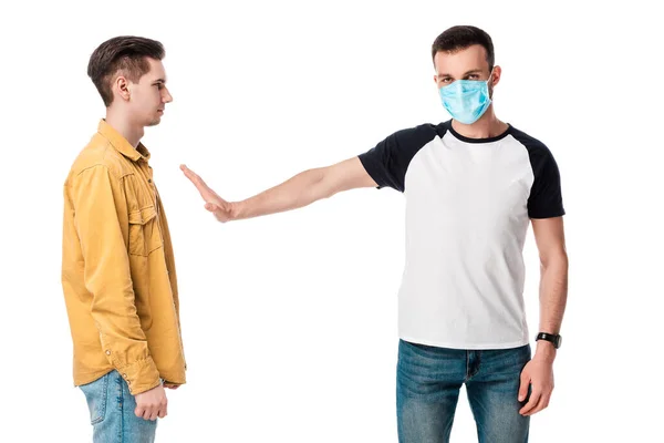 Man in medical mask showing stop gesture near guy isolated on white — Stock Photo