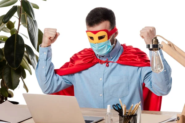 Freelancer in medical mask and superhero cloak using laptop isolated on white — Stock Photo