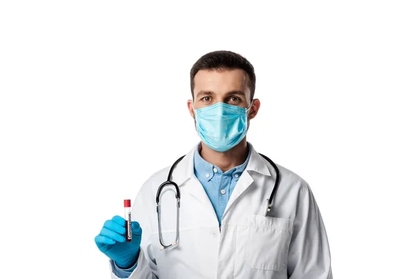 Doctor in medical mask and white coat holding test tube with sample and coronavirus lettering isolated on white — Stock Photo