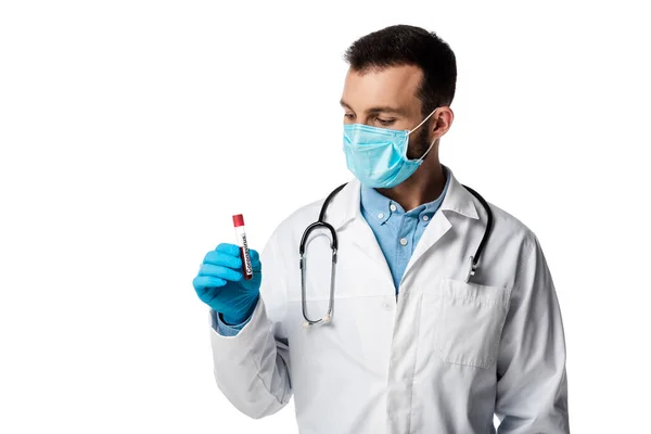 Doctor in medical mask and white coat looking at test tube with sample and coronavirus lettering isolated on white — Stock Photo