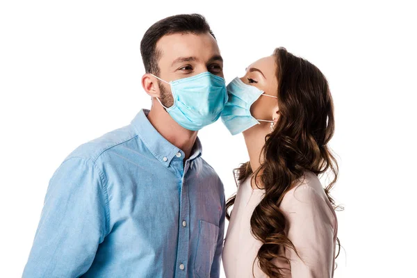 Жінка цілує чоловіка в медичній масці ізольовано на білому — стокове фото