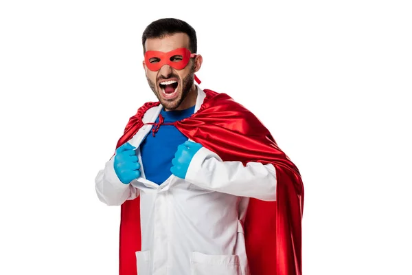 Médico emocional en traje de superhéroe quitándose la bata blanca aislado en blanco - foto de stock