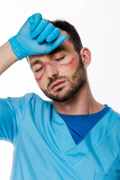 Müder Arzt mit Flecken im Gesicht und geschlossenen Augen, die Stirn berühren, isoliert auf weißem Grund — Stockfoto