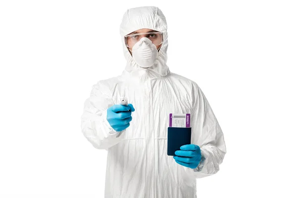 Man in hazmat suit holding pyrometer and passport with boarding pass isolated on white — Stock Photo