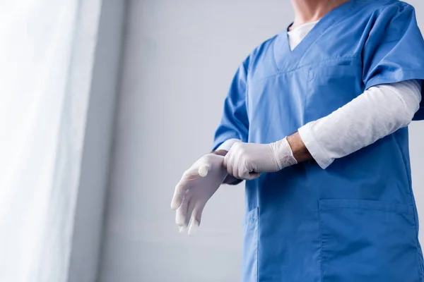 Cropped view of mature doctor wearing latex glove on white — Stock Photo