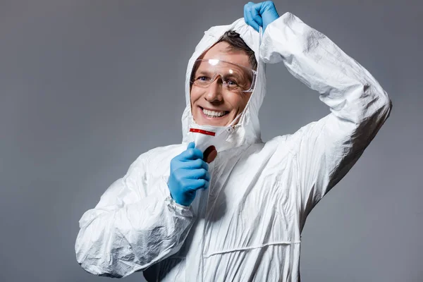 Cheerful and mature man in hazmat suit and goggles isolated on grey — Stock Photo