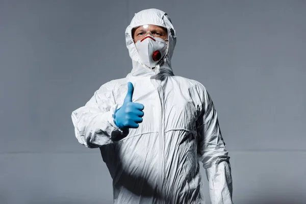 Homem em equipamento de proteção individual mostrando polegar para cima em cinza — Fotografia de Stock