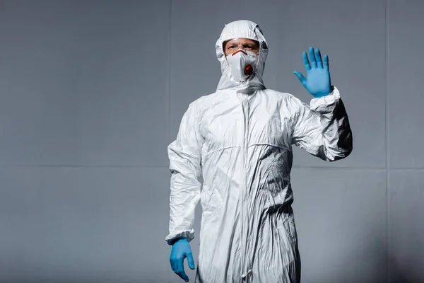 Mann in persönlicher Schutzausrüstung winkt mit der Hand auf grau — Stockfoto