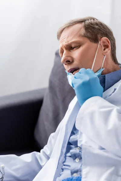 Exhausto y maduro médico tocando máscara médica — Stock Photo