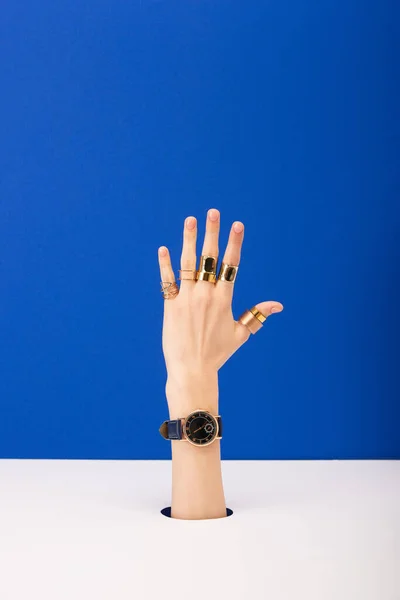 Vista recortada de la mujer con reloj de pulsera y anillos aislados en azul - foto de stock