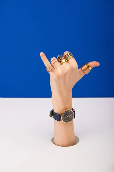 Corte vista de mulher com relógio de pulso e anéis dourados mostrando chamar-me gesto isolado no azul — Fotografia de Stock