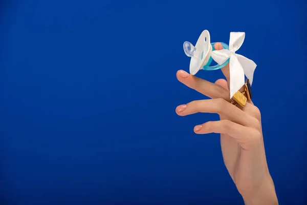 Cropped view of woman holding silicone pacifier on blue — Stock Photo