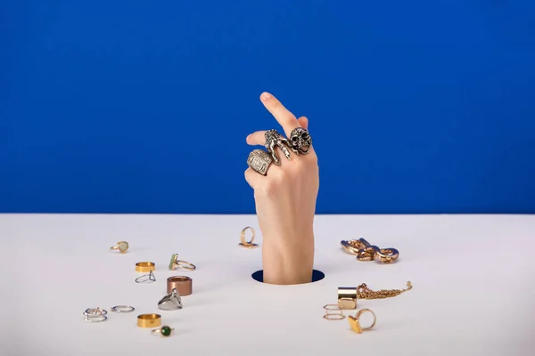 Vista recortada de la mujer con pulsera en la mano cerca de anillos aislados en azul - foto de stock