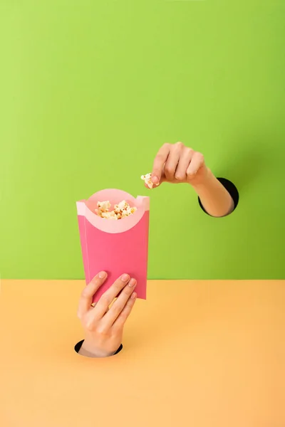 Vue recadrée de la femme tenant bouquet avec pop-corn sur vert et orange — Photo de stock