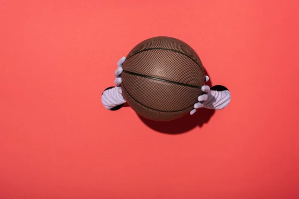 Vista cortada de mulher em luvas segurando basquete no vermelho — Fotografia de Stock