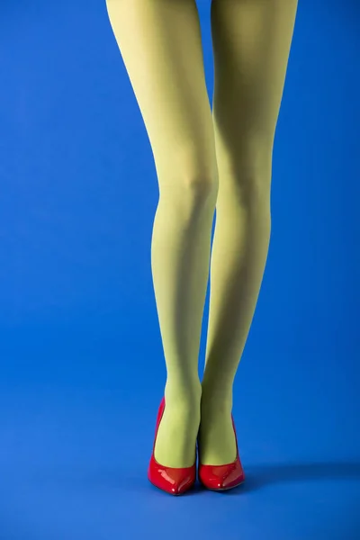 Cropped view of model in green tights standing on blue — Stock Photo