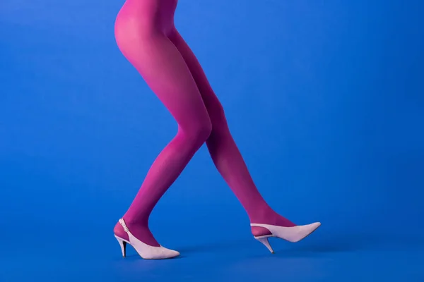 Cropped view of model in bright purple tights and shoes posing on blue — Stock Photo