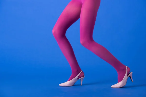 Vue recadrée de la femme en collants violets et chaussures posant sur bleu — Photo de stock