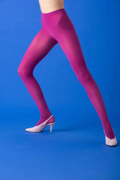 Cropped view of woman in bright purple tights and heels standing on blue — Stock Photo