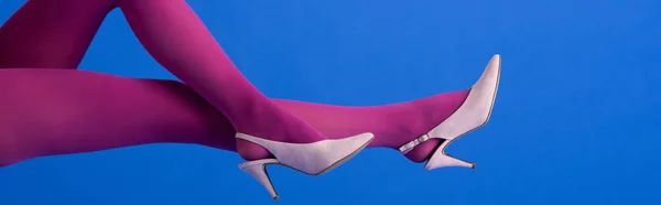 Panoramaaufnahme einer Frau in leuchtend lila Strumpfhosen und Schuhen, die auf blau posiert — Stockfoto