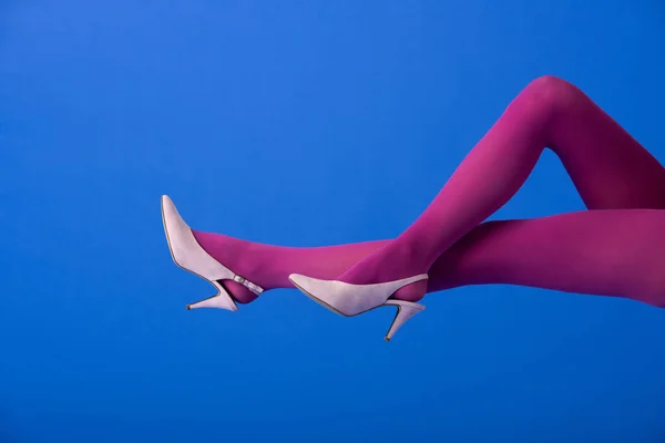 Cropped view of model in bright purple tights and shoes posing on blue — Stock Photo