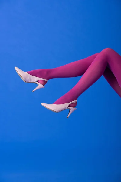 Cropped view of model in purple tights and heels posing on blue — Stock Photo