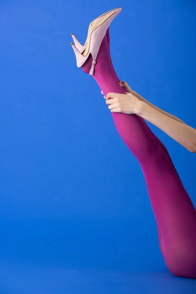 Abgeschnittene Ansicht des Modells, das helle lila Strumpfhosen auf Blau berührt — Stockfoto