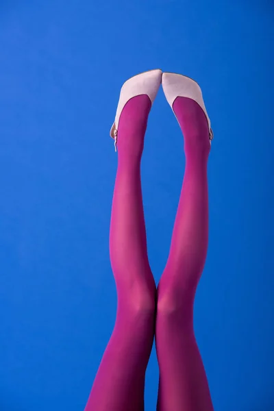 Vista recortada del modelo en púrpura medias y calzado posando en azul - foto de stock