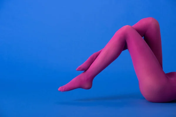 Cropped view of woman in colorful purple tights posing on blue — Stock Photo