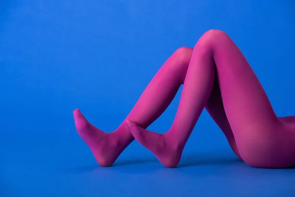 Vista recortada del modelo en medias púrpura brillante posando en azul - foto de stock