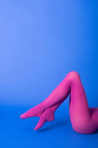 Vista ritagliata della donna in collant viola brillante in posa su blu — Foto stock