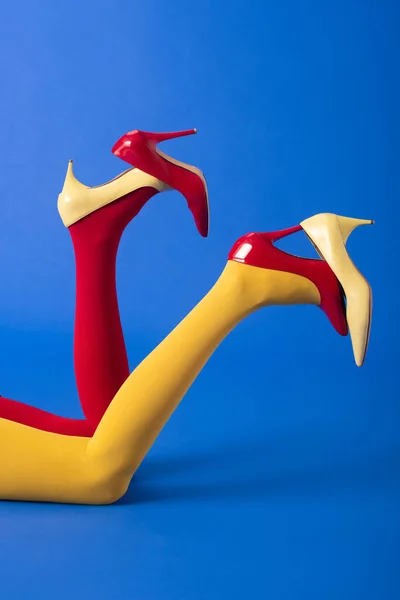 Обрезанный вид женщины в красных и желтых колготках и обуви на синий — стоковое фото