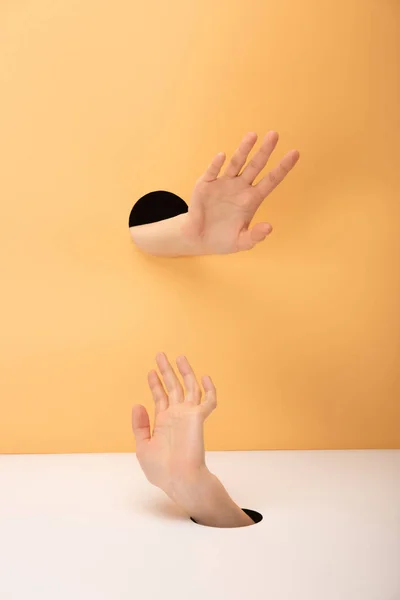 Cropped view of woman gesturing with hands on orange and white — Stock Photo