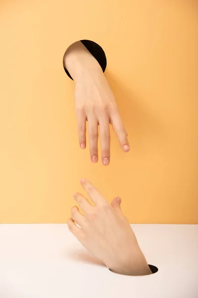 Ausgeschnittene Ansicht der Hände auf orange und weiß — Stockfoto
