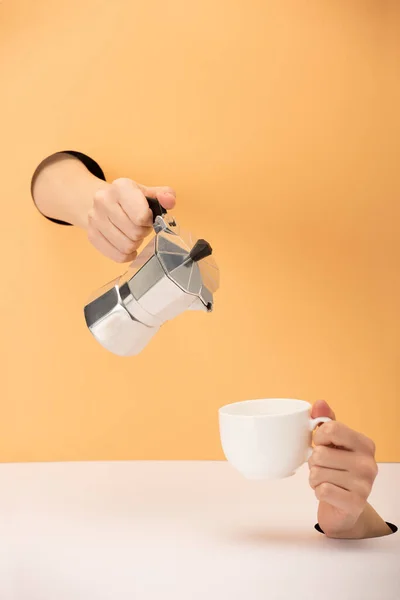Vista cortada da mulher segurando panela de café com xícara em laranja e branco — Stock Photo