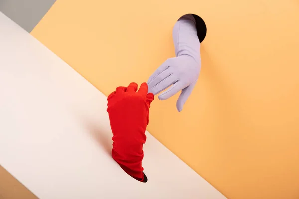 Mãos vista cortada em luvas e buracos em laranja e branco — Fotografia de Stock