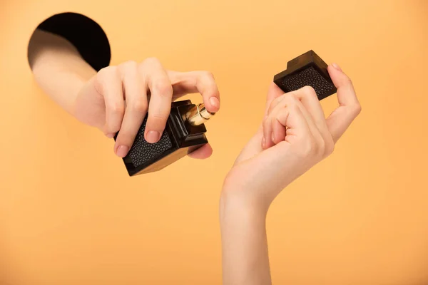 Ausgeschnittene Ansicht einer Frau mit Parfümflasche auf Orange — Stockfoto