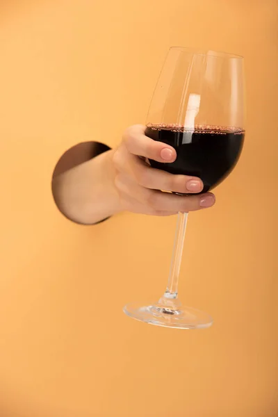 Vista cortada de mulher segurando copo de vinho de vinho tinto em laranja — Fotografia de Stock