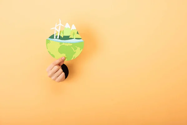 Cropped view of hand holding paper cut with planet on orange — Stock Photo