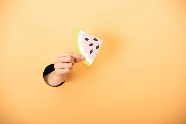 Cropped view of woman holding paper watermelon on orange — Stock Photo