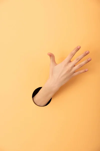 Vue recadrée du trou avec la main de la femme sur orange — Photo de stock