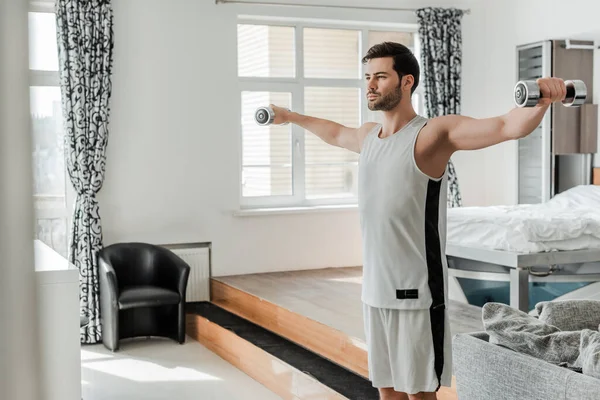 Enfoque selectivo del hombre que hace ejercicio con las barras en casa - foto de stock