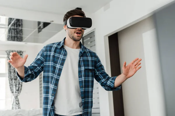 Excited man using virtual reality headset in living room — Stock Photo