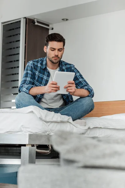 Selektiver Fokus des Mannes mit gekreuzten Beinen mittels digitaler Tablette auf dem Bett — Stockfoto