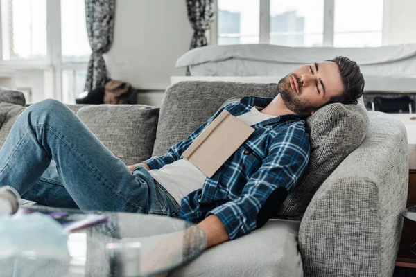 Selektiver Fokus des Mannes mit Buch, das auf der heimischen Couch schläft — Stockfoto