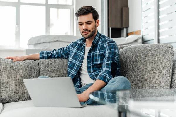 Foco seletivo de freelancer em camisa entrelaçada trabalhando em laptop em casa — Fotografia de Stock