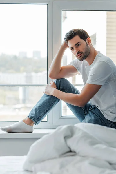 Selective focus of man sitting on windowsill in bedroom — Stock Photo