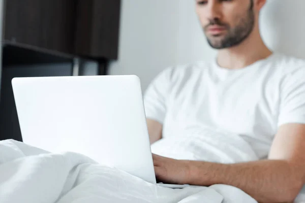 Selective focus of freelancer using laptop on bed — Stock Photo