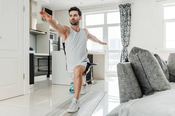Красивий чоловік у спортивному одязі робить легені під час тренувань вдома — стокове фото